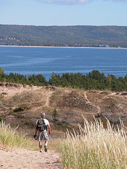 A hiker enjoys the panaromic view from a trail in Sleeping Bear Dunes National Lakeshore.