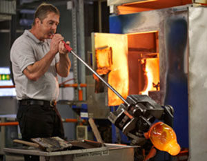 A worker blows molten crystal into a vase at House of Waterford.