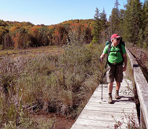 A hiker crossing the old boardwalk along the Jordan River Pathway.